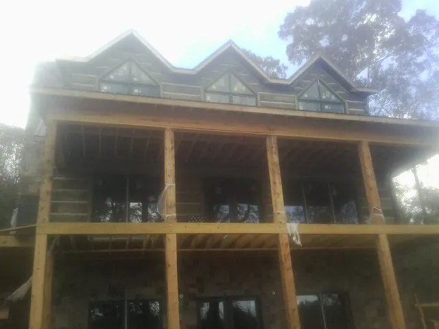 Dormers and porch framing on a large log home under construction — Roof Coating work by our crew in Ryde